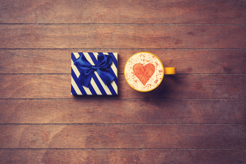 Cup of Cappuccino with heart shape symbol and gift box on wooden background